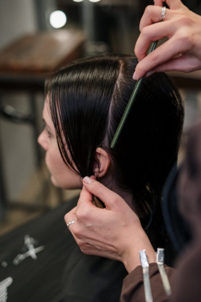 Close-up of a hairstylist sectioning a woman's wet hair in a salon.