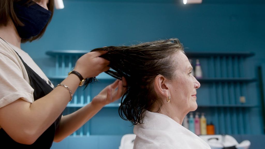 An elderly woman enjoying a stylish hair treatment by a professional hairstylist in a salon.